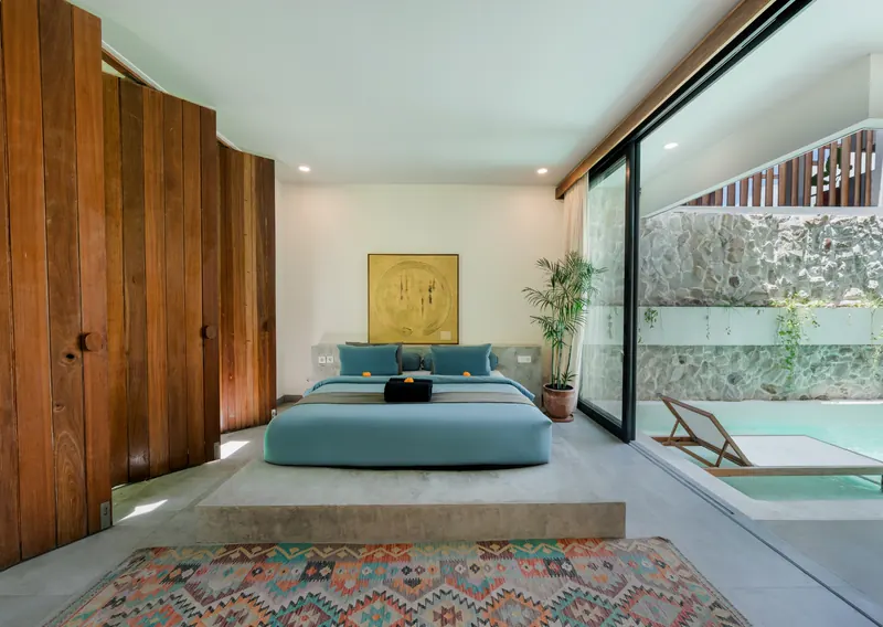 Bedroom in Bali with a natural stone feature wall and timber screens