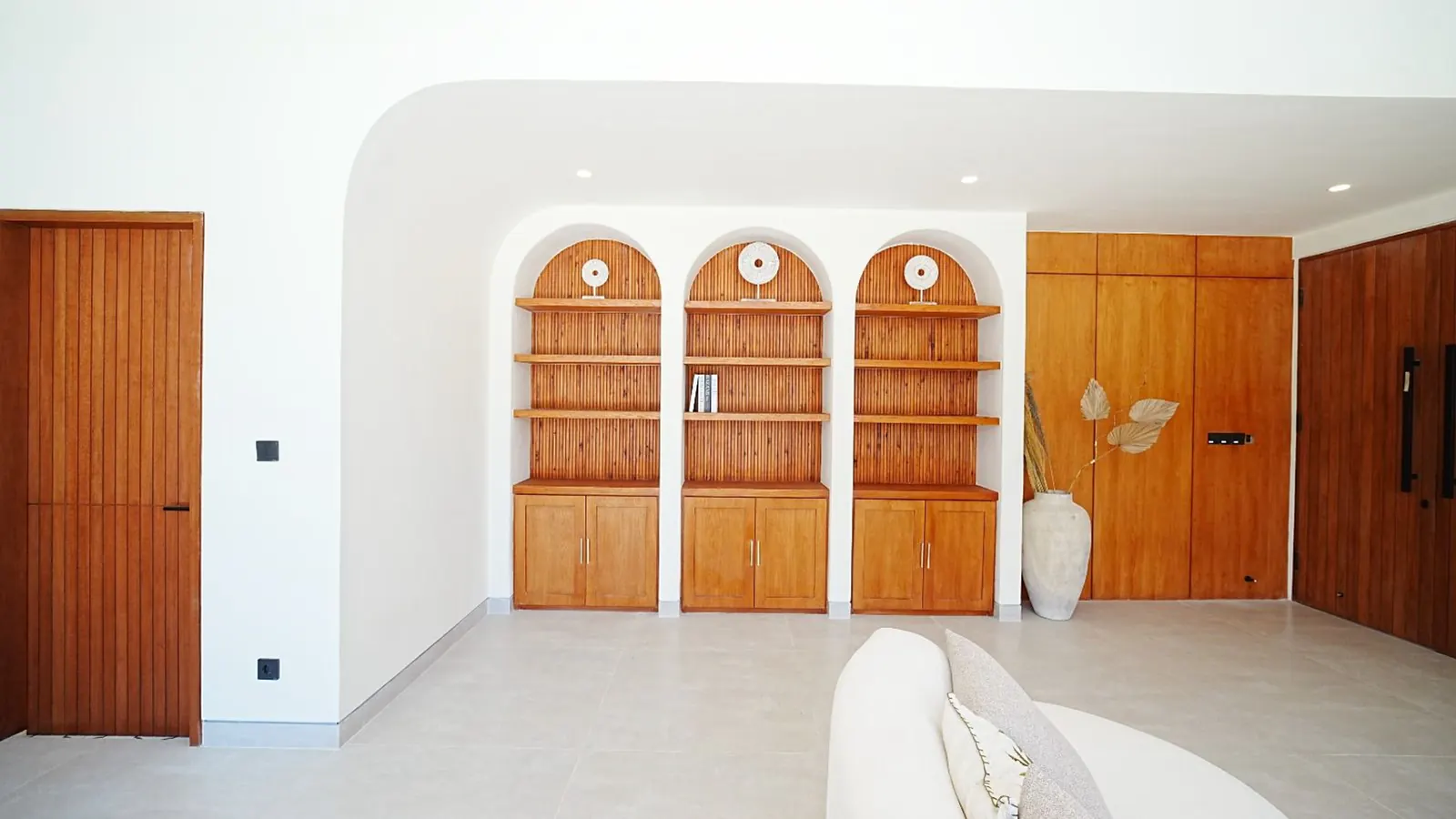 Built-in arched teak cabinets in a white living room