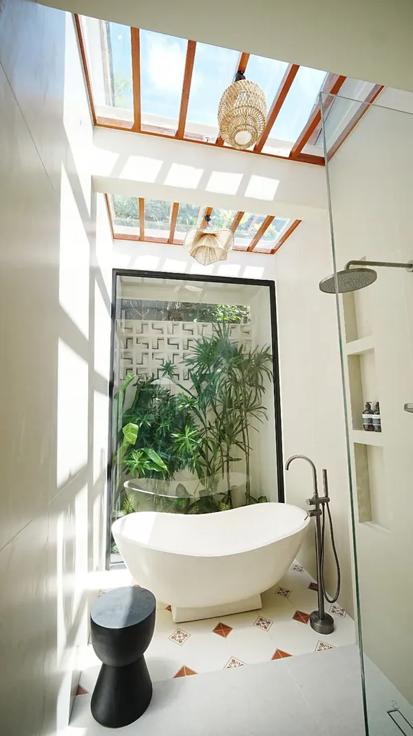Freestanding bathtub under a skylight with tropical plants in a Bali bathroom